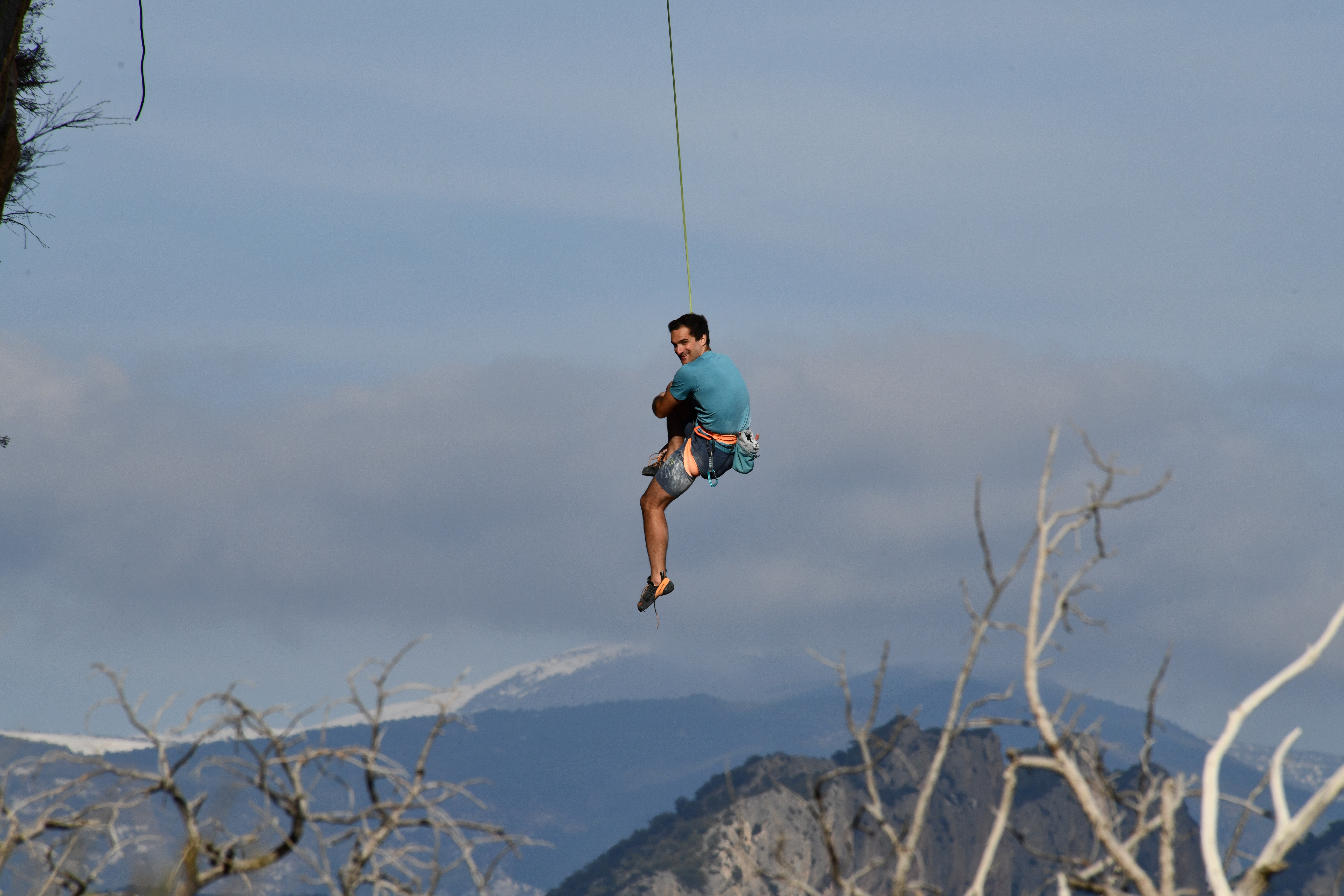 Matteo Menardi Ménego — climbing in a quiet moment, suspended on a green rope against alpine sky